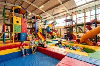 Vue d'ensemble d'une aire de jeux couverte en Île-de-France avec structures colorées et familles